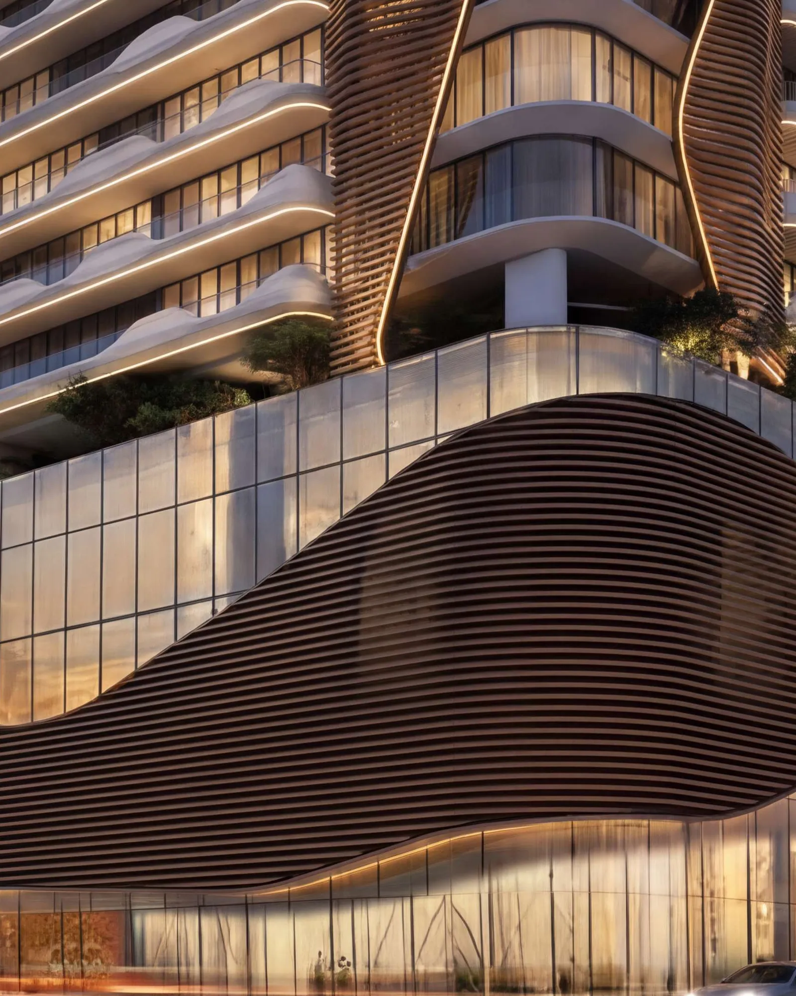 The tower's curving podium and glowing balconies lit up at night